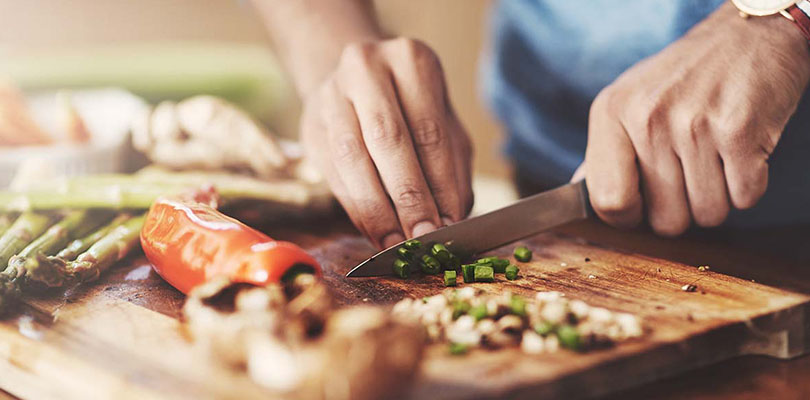 A man is cutting green onions on a cutting board